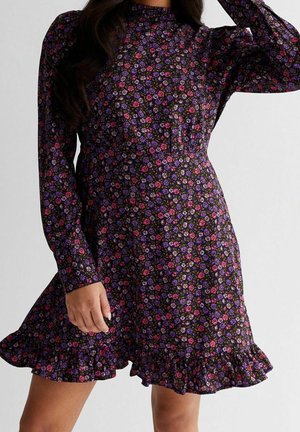 Schwarzes Blumenkleid mit langen Ärmeln, verziert mit lila, rosa und weißen Blumen, tailliert und mit einem volanartigen Saum am Rock.