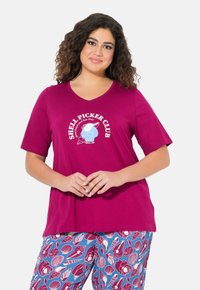 Camiseta magenta con cuello en V y gráfico "Shell Picker Club", combinada con pantalones de pijama azul claro que presentan diversos patrones de conchas.
