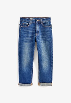 Jean en denim bleu coupe ample avec poches avant et poche monnaie, coutures visibles et revers roulés sur fond blanc.