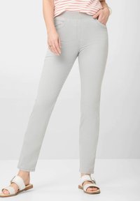 Lichtgrijze pull-on broek met een strakke pasvorm, voorzien van zijzakken, een soepele structuur en een strakke lijnontwerp, gecombineerd met witte sandalen.