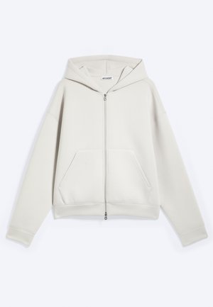 Felpa con cappuccio beige chiaro con zip, maniche lunghe e tasche frontali, mostrata distesa su sfondo bianco.