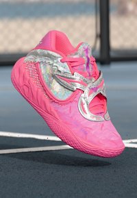 Jasně růžová sportovní obuv s texturovaným povrchem, metalickými stříbrnými akcenty, síťovaným svrškem a složitými detaily na podrážce a stranách.