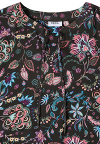 Tissu noir avec motif floral coloré en rose, bleu, vert et violet, présentant un col rond avec une fente et des liens à nouer.