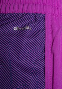 Kankaan Climalite, jossa on eläväinen violetti rakenne ja kuvioitu sisäkerros, jossa on viistoja raitoja eri violetti sävyissä.