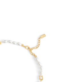 Gold-tone necklace featuring irregular pearls, a lobster clasp, and a chain with a tag. Textured surface and varied pearl shapes enhance design.