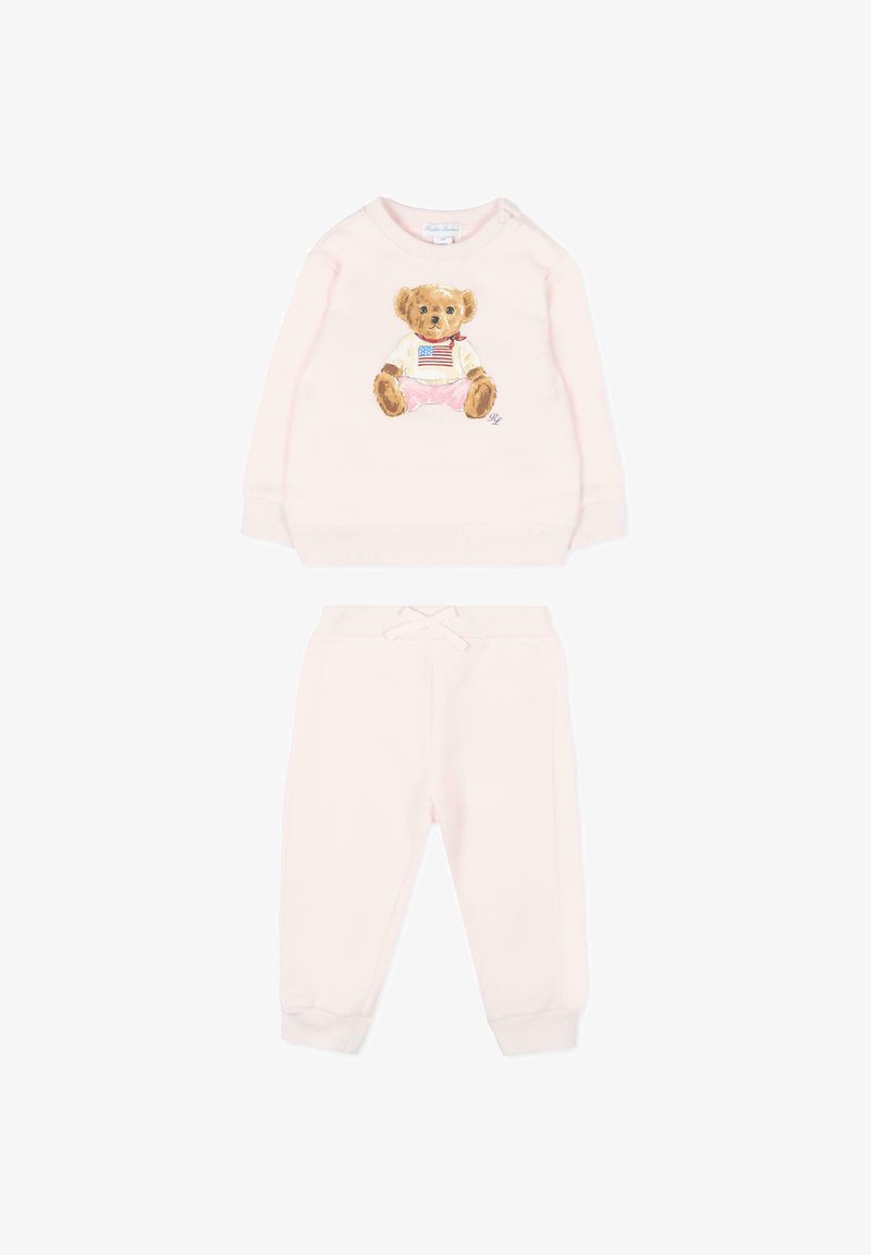 Ensemble sweat-shirt et pantalon rose clair pour tout-petit, le sweat-shirt présente un ours en peluche portant un t-shirt avec le drapeau américain et un short rose.
