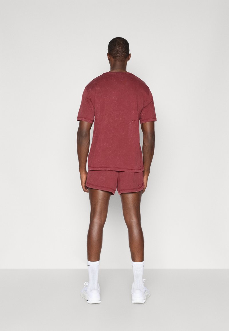 Weinrot strukturiertes kurzärmliges Hemd und passende Shorts. Mit Logodetails und kombiniert mit weißen Socken und Turnschuhen. Einfaches Design.