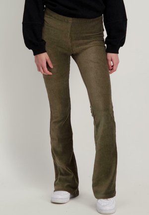 Olijfgroene corduroy flare pants met verticale ribbelstructuur, een middelhoge taille en een gladde afwerking, gecombineerd met witte sneakers.