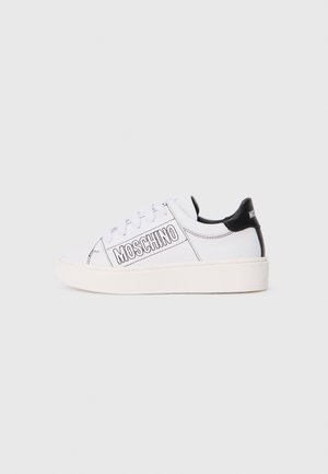 Hvide lave sneakers med sort hælklap, "MOSCHINO" logo på siden, hvide snørebånd og tyk off-white sål mod en ensfarvet baggrund.