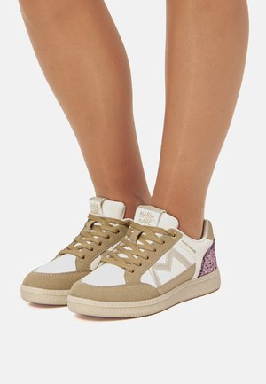 Zapatillas beige y blancas con un acabado de ante texturizado, que cuentan con un acento de brillo y una suela de goma. Diseño de cordones con una marca en la lengua.