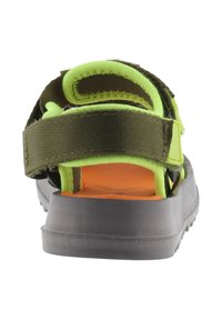 Vista trasera de sandalia verde y negra con correas ajustables, suela texturizada y plantilla naranja. Materiales duraderos diseñados para la comodidad.