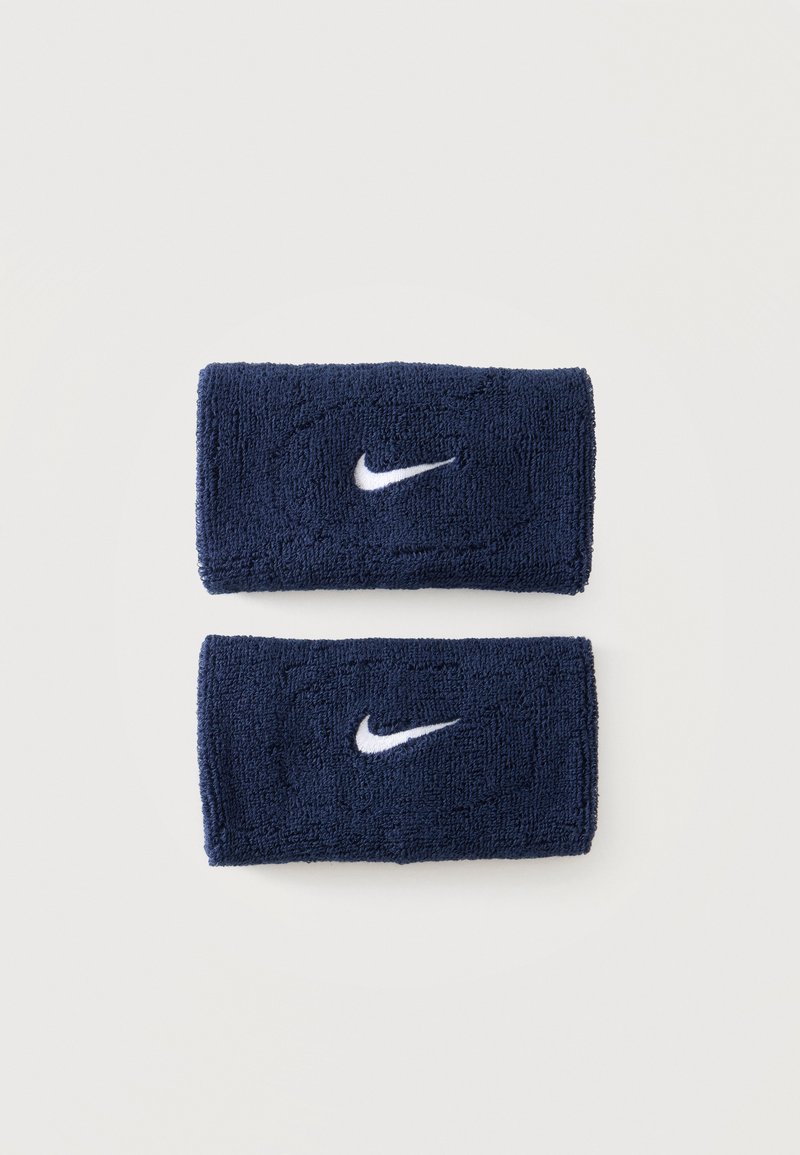 Δύο ναυτικά μπλε βραχιόλια Nike με λευκά λογότυπα Swoosh τοποθετημένα σε λευκή επιφάνεια.