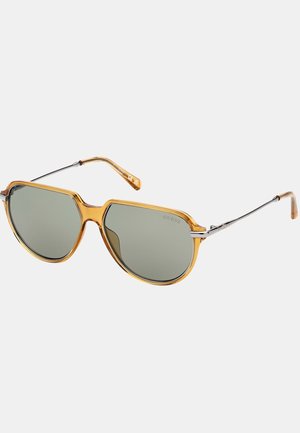 Occhiali da sole aviator con una montatura trasparente color ambra, lenti grigie e dettagli in metallo argento sulle astine.