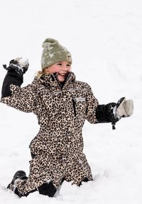 Bambino con tuta da neve con stampa leopardata e cappello verde inginocchiato nella neve, sorridente, pronto a lanciare una palla di neve con le mani guantate.