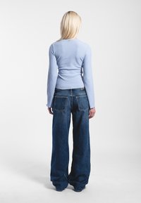 Ljusblå ribbad långärmad topp som kombineras med löst sittande mörkblå denimjeans, med rak passform och framträdande bakfickor.