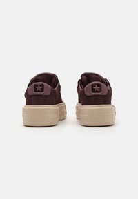 Baskets en daim bordeaux foncé avec une semelle en caoutchouc beige, dotées d'une étoile en accent et d'un talon texturé, conçues pour un usage décontracté.