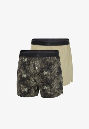 Twee herenboxershorts met zwarte elastische taillebanden, één in beige en één met een zwart-grijs camouflagepatroon.