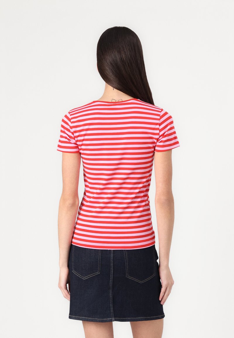 T-shirt à manches courtes rayé rouge et blanc avec une coupe ajustée, porté avec une jupe en denim sombre. La vue de dos montre le motif à rayures et l'encolure.