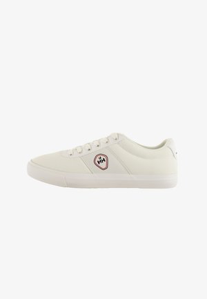 Zapatilla blanca con parte superior de lona texturizada, cordones en tono, suela de goma y un parche logo rojo y negro en el lado.