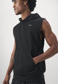 Fekete ujjatlan kapucnis pulóver puha anyagból, elülső zsebbel, minimalista logóval a mellrészen és laza szabású dizájnnal.