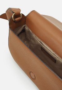 Borsa a mano in pelle marrone con texture liscia, dotata di un ampio interno e chiusura a bottone. Include un dettaglio in metallo color oro.