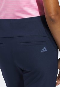 Αθλητικά παντελόνια σε ναυτικό μπλε με ομαλή υφή, που διαθέτουν πίσω τσέπες και ένα διακριτικό γκρι λογότυπο Adidas στην αριστερή πλευρά.