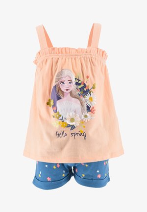 Helles pfirsichfarbenes Tanktop mit elastischem Ausschnitt, verziert mit einem floralen Grafikdesign und dem Text "Hallo Frühling". Dazu werden blaue Shorts getragen, die mit kleinen Blumen geschmückt sind.