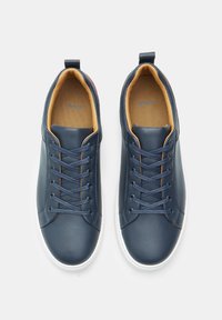 Marineblaue Leder-Sneaker mit runder Zehenkappe, weißer Gummisohle und kontrastierendem, hellbraunem Innenbereich. Verfügt über sechs Ösen mit passenden Schnürsenkeln und ein minimalistisches Design.