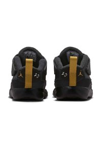 Zapatillas deportivas negras con detalles en dorado, con parte superior texturizada, tirador en el talón y el número "23" en la parte trasera.