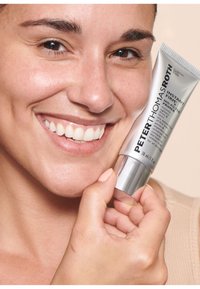Tubo argento del primer Instant Firmx No. 11 di Peter Thomas Roth tenuto contro la pelle, caratterizzato da un design elegante, una texture liscia e un'etichettatura chiara.