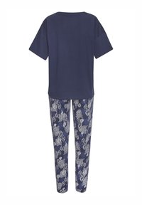 Navy-Bluse mit kurzen Ärmeln kombiniert mit gemusterten Pyjamahosen, die weiße Blatttropfenmuster auf einem dunkelblauen Hintergrund zeigen.
