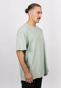 Light green oversized t-shirt made from soft fabric. Features a round neck and short sleeves. Plain design with no visible patterns or accents.
