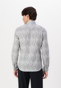 Langermet skjorte i lys grå med blomstermønster som har blå detaljer. Slim fit med rund skjortekrage og knappemanchetter. Glatt tekstur.