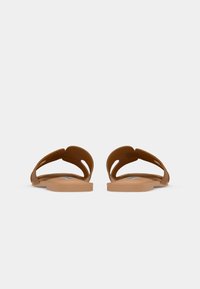 Brune gummisandaler med en glat overflade, åben tå-design og udskæringer på stropperne. Flade såler med minimal struktur.