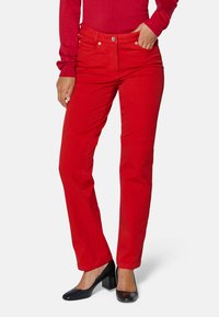 Rote Baumwollmischhose mit geradem Bein, im Fünf-Taschen-Stil und silberfarbenen Beschlägen, kombiniert mit schwarzen Blockabsatzschuhen.