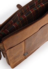 Brun læder messenger taske med lynlåslukning, der har et ternet foer i rød, grøn og gul. Indeholder en forlomme og dekorative metaldetaljer.