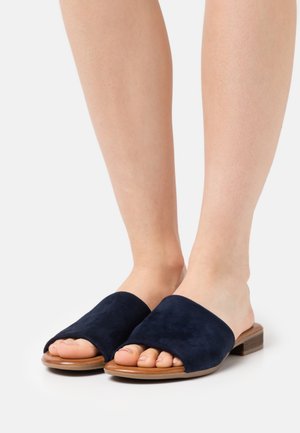 Navy suede slide sandals with an open toe, flat wooden sole, and wide upper strap covering part of the foot.