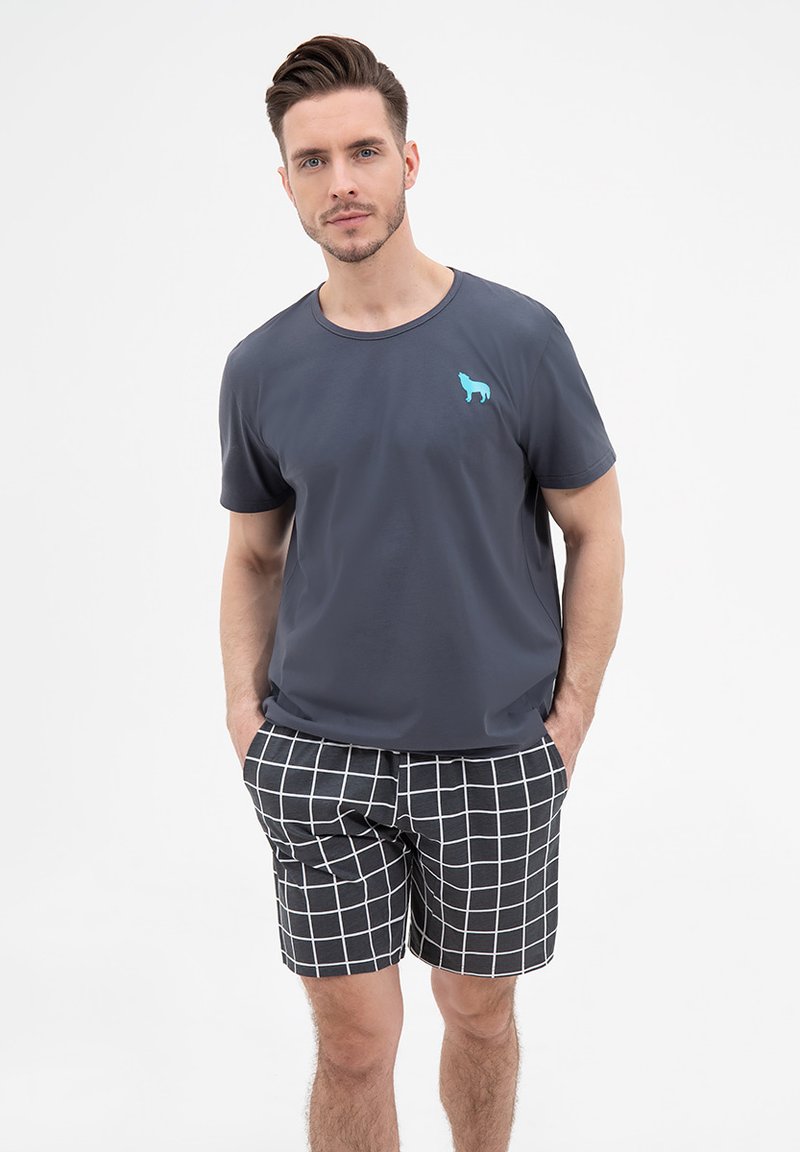 Męska ciemnoszara koszulka z okrągłym dekoltem oraz niebieskim logo psa, w zestawie z czarnymi szortami z białym wzorem w kratkę.