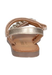 Bronzen platte sandalen met een textuur op de banden, voorzien van metallic accenten en een zachte zool. De achterkant benadrukt de dubbele banden en de eenvoudige vorm.