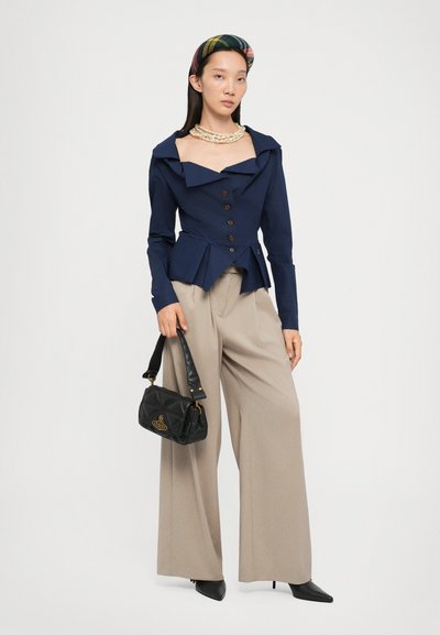 Navy tailored jacket with a wide collar and button front, paired with beige wide-leg trousers. Black quilted handbag with gold logo detail.