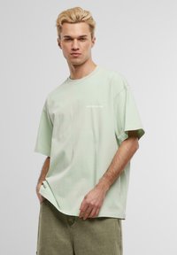 Heled roheline puuvillane T-särk lühikeste varrukatega, mugav lõige ning ees väike trükitud logo "ANOTHER COTTON". Lihtne disain.