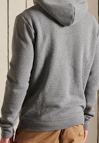 Grijze hoodie gemaakt van zachte stof, met een eenvoudig ontwerp, geribde manchetten en zoom, en een kangoeroezak.