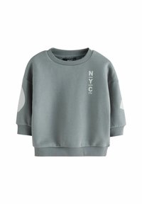 Bluza scurtă gri, confecționată dintr-un material din amestec de bumbac. Are un decolteu rotund, mâneci supradimensionate și un text imprimat "NYC" în culoare contrastantă.