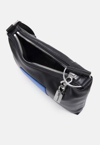  svart läderväska med en blå accent, med en silvrig dragkedjestängning och beslag. Inuti verkar väskan vara fodrad och rymlig. Kompakt design.