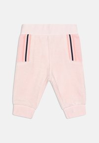 Jogging en velours rose avec une texture douce, featuring taille élastique et accents rayés sur les poches. Design de jambe fuselée avec des poignets côtelés.