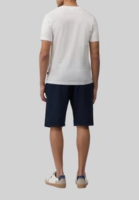 Witte korte mouwen t-shirt, marineblauwe shorts en witte sneakers met marineblauwe accenten, gezien vanuit de achterkant. Minimalistisch ontwerp, katoenmix stof.
