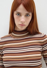 Gestreifter, gerippter Rollkragenpullover in Braun, Creme und Beige. Verfügt über ein tailliertes Design und einen hohen Kragen. Glatte Textur.