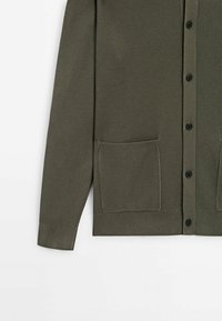 Olive green ribbed cardigan with a button front, two front pockets, and ribbed cuffs. Made from a textured knit fabric.