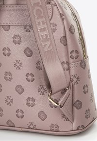 Jasnofioletowa torebka z wytłaczanym wzorem różnych symboli. Posiada złoty zamek błyskawiczny oraz materiałowy pasek na ramię z logo.