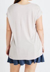 Ljusgrå kortärmad t-shirt med en avslappnad passform, mjuk textur och rundad halsringning, tillsammans med en denimkjol med flared design.